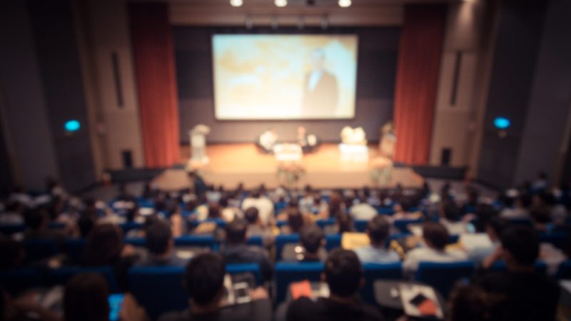 Disfocus of the speaker giving a talk on corporate Business Conference. Audience at the conference hall. Business and Entrepreneurship event